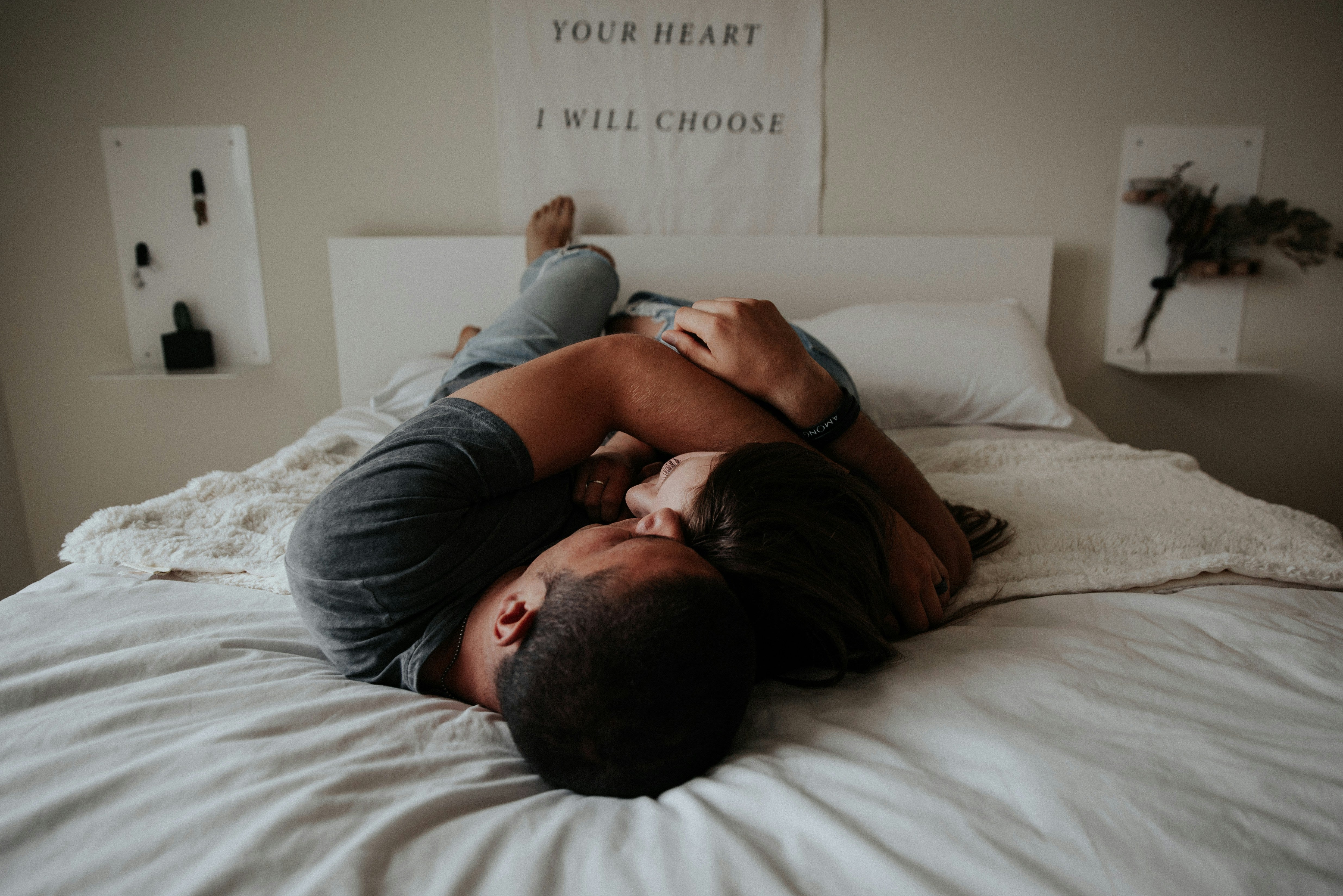 A couple lying close on a bed with soft lighting, faces not visible