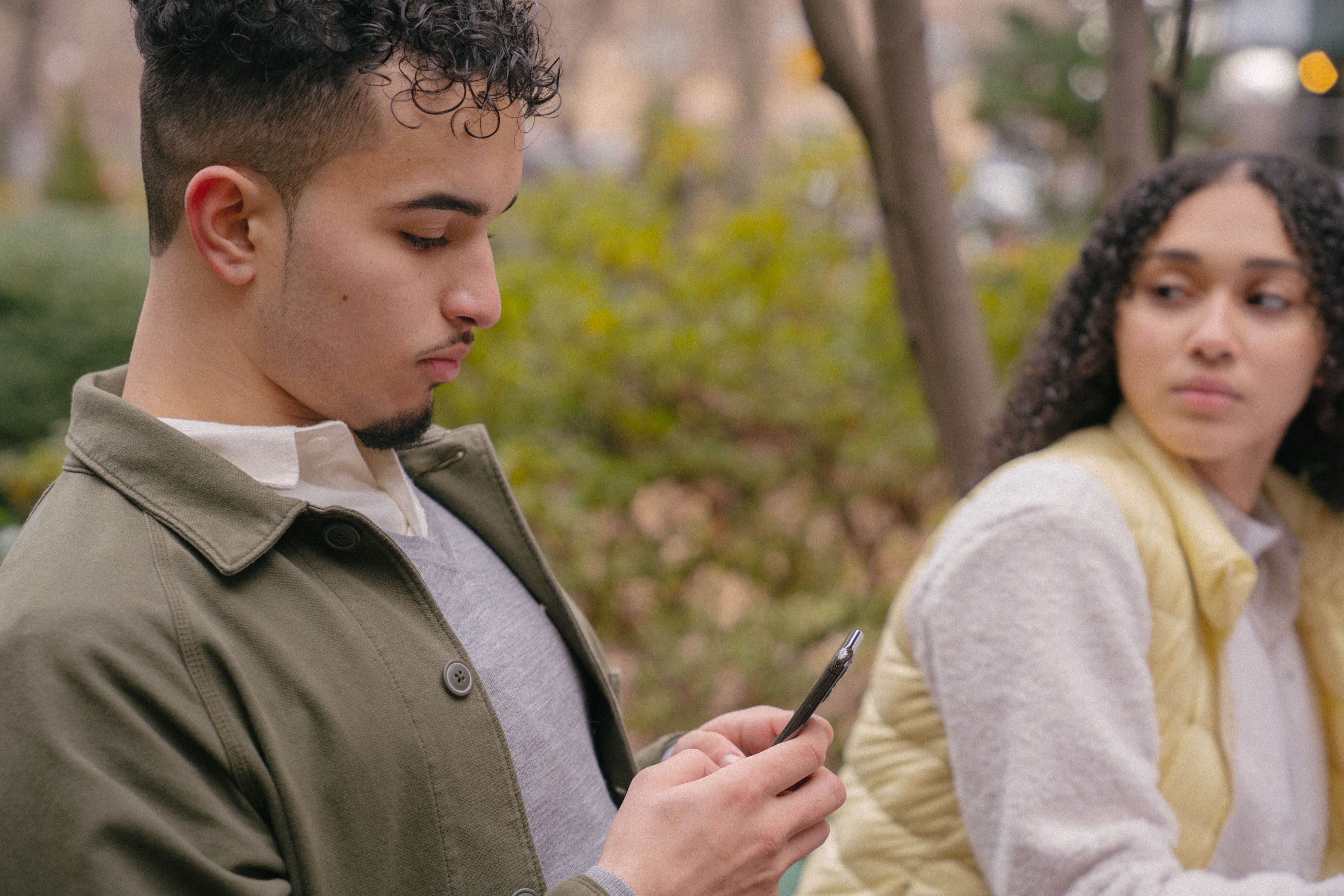 A man sneakily texting someone else while sitting with his partner