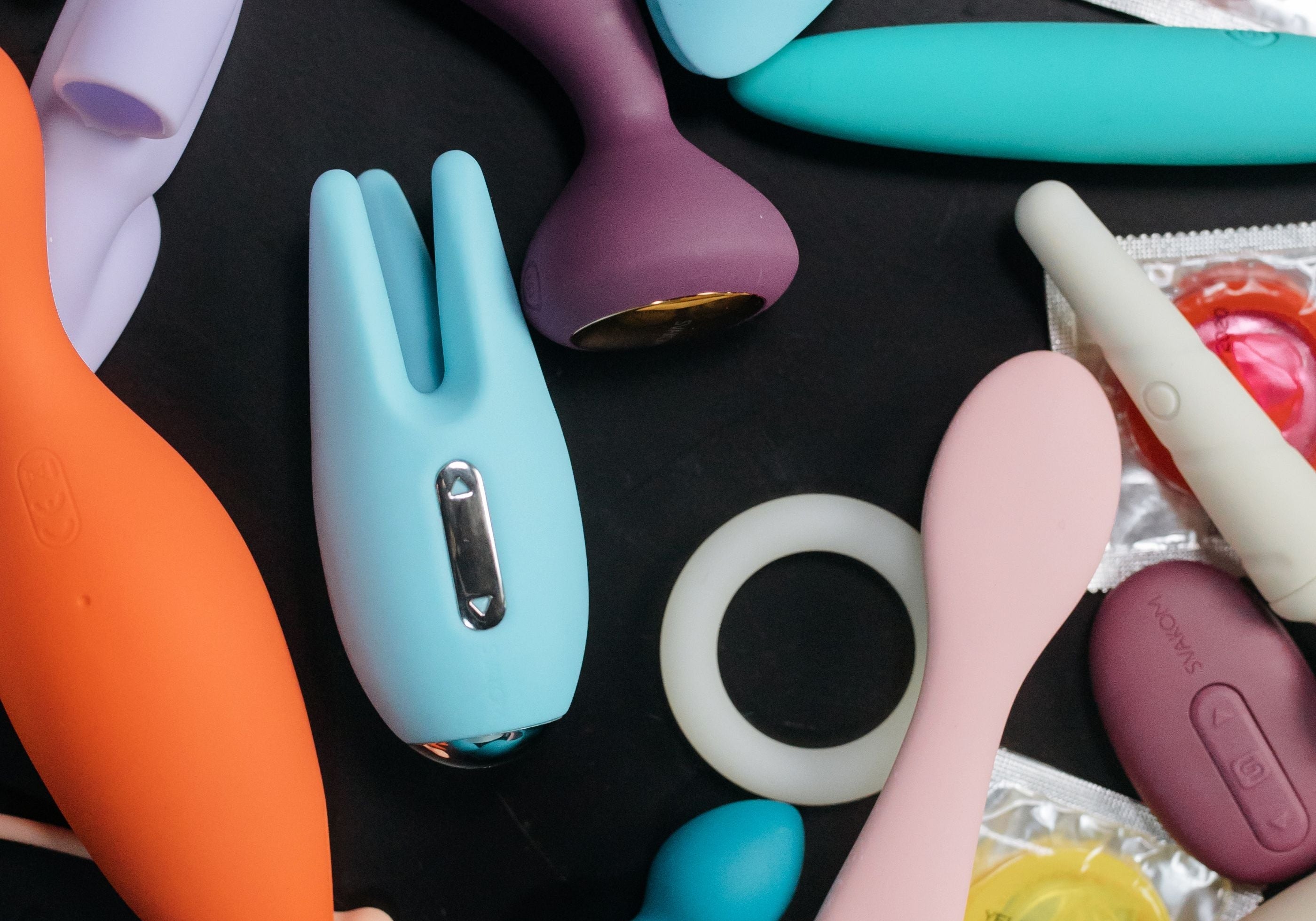 A condom packet beside silicone massagers and vibrators