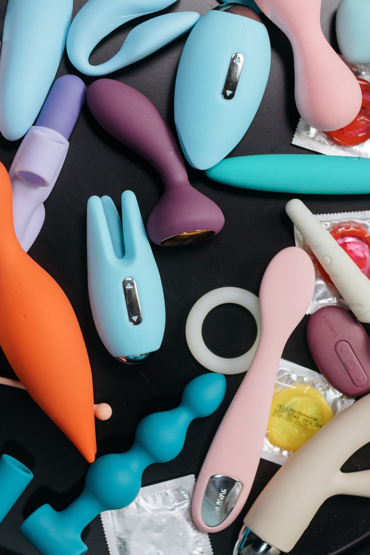 A condom packet beside silicone massagers and vibrators