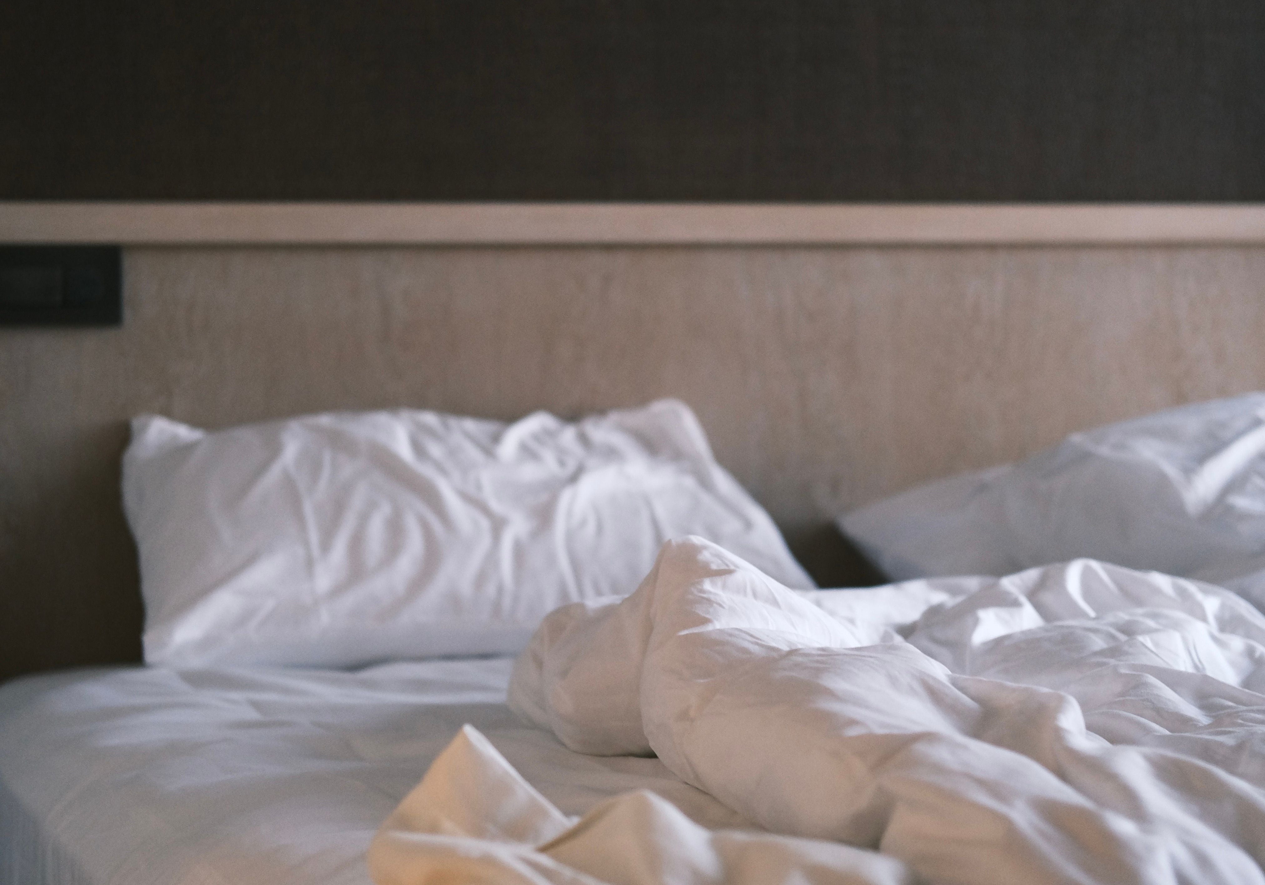 A quiet bedroom in soft low light, unmade bed