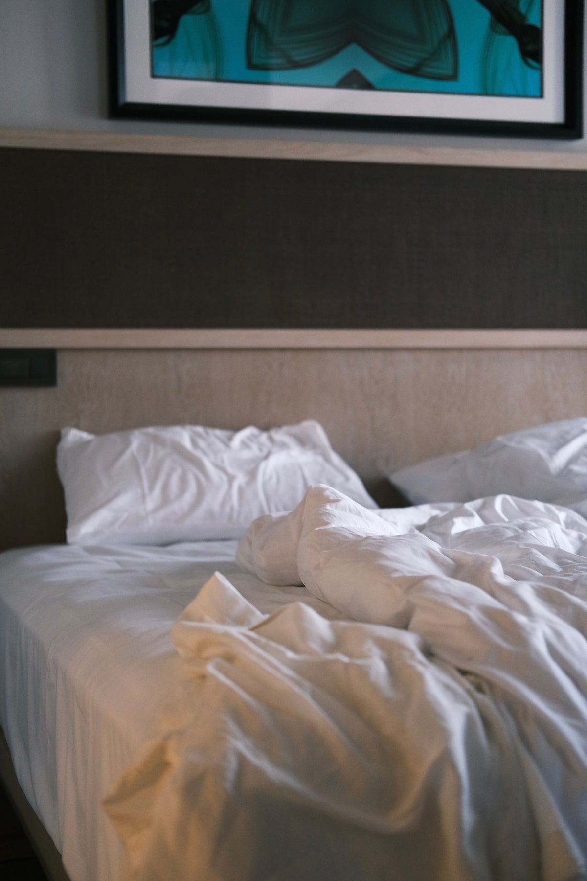 A quiet bedroom in soft low light, unmade bed